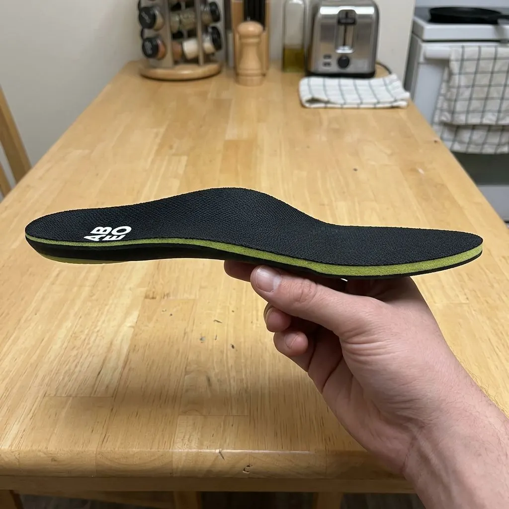 ABEO Premium Orthotic insole flexed by hand, showing the molded arch bending and recovering its shape