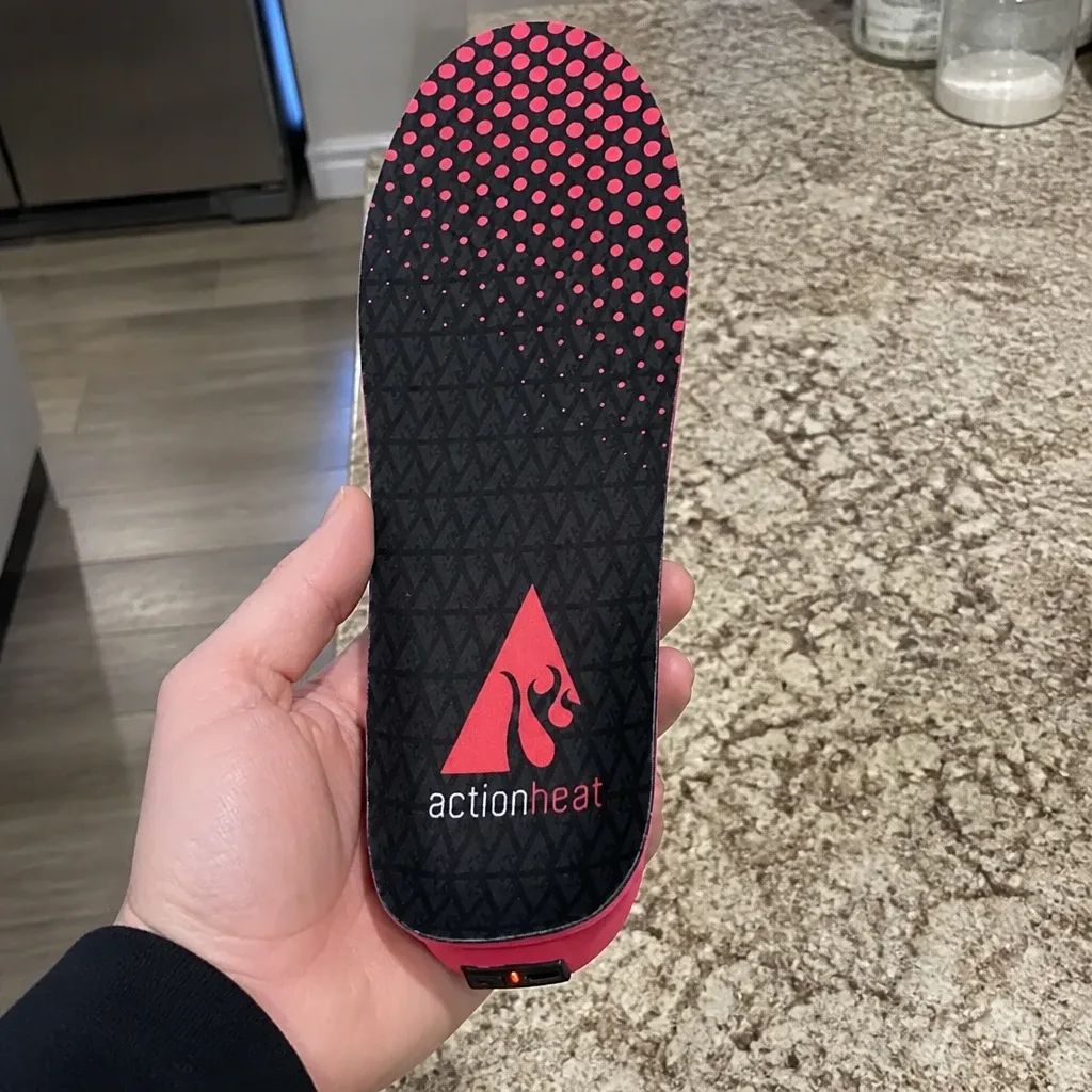 An ActionHeat heated insole held in hand, showing the fleece-lined top and heating panel