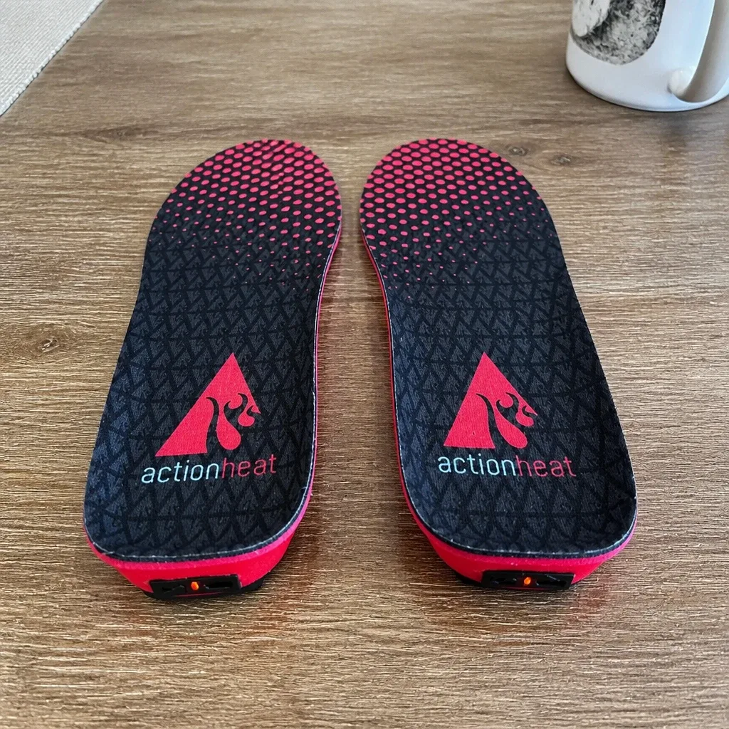 ActionHeat heated insoles laid out on a kitchen table with the remote and charging cable