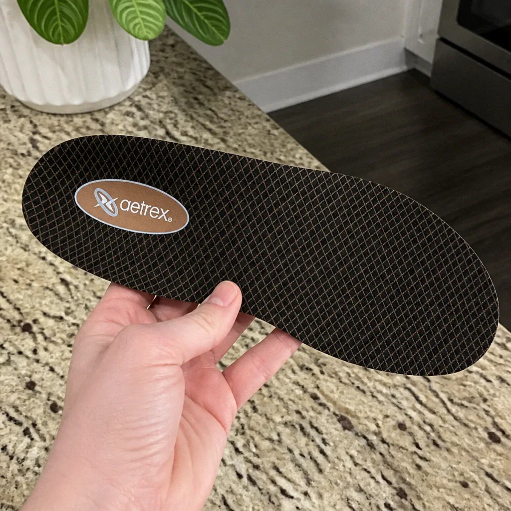 An Aetrex Lynco L400 Compete orthotic insole held in hand, showing the CopperGuard top cover