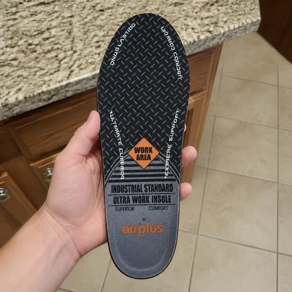 An Airplus Ultra Work Memory Plus insole held up in hand showing the fabric top cover and foam core