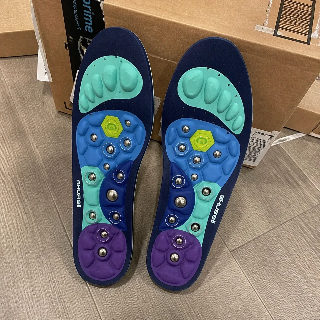 A pair of Akusoli magnetic acupressure insoles next to their retail box on the floor