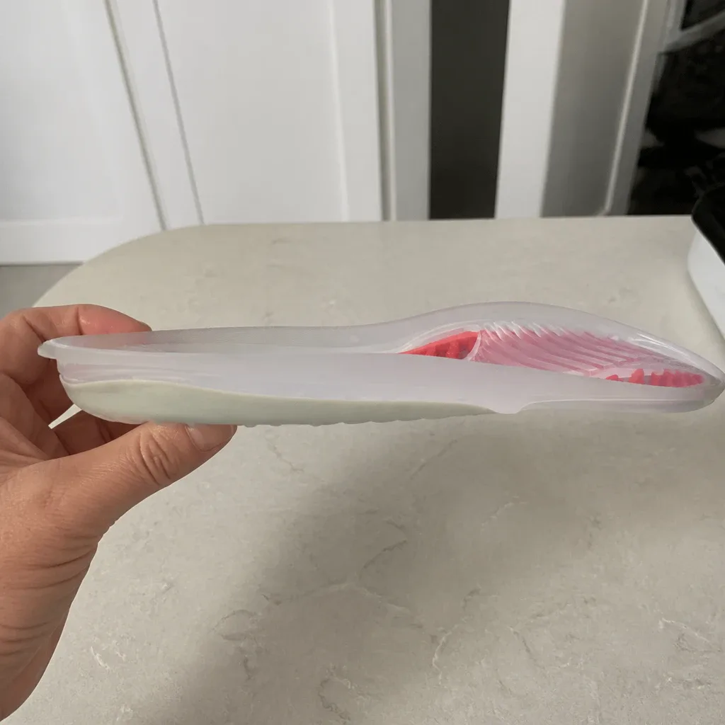 An Aline Red All Day insole held sideways, showing the arch profile and heel cup