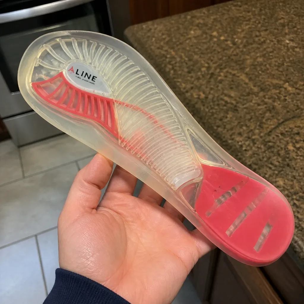 An Aline Red All Day insole held in hand, showing the rib-and-suspension shell