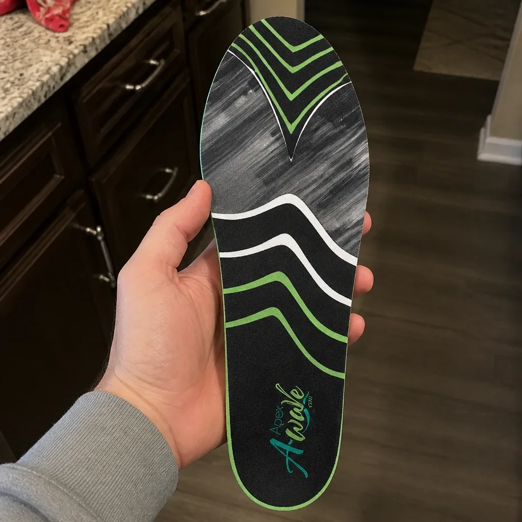 An Apex A-Wave Firm orthotic insole held in hand, showing the memory foam top layer