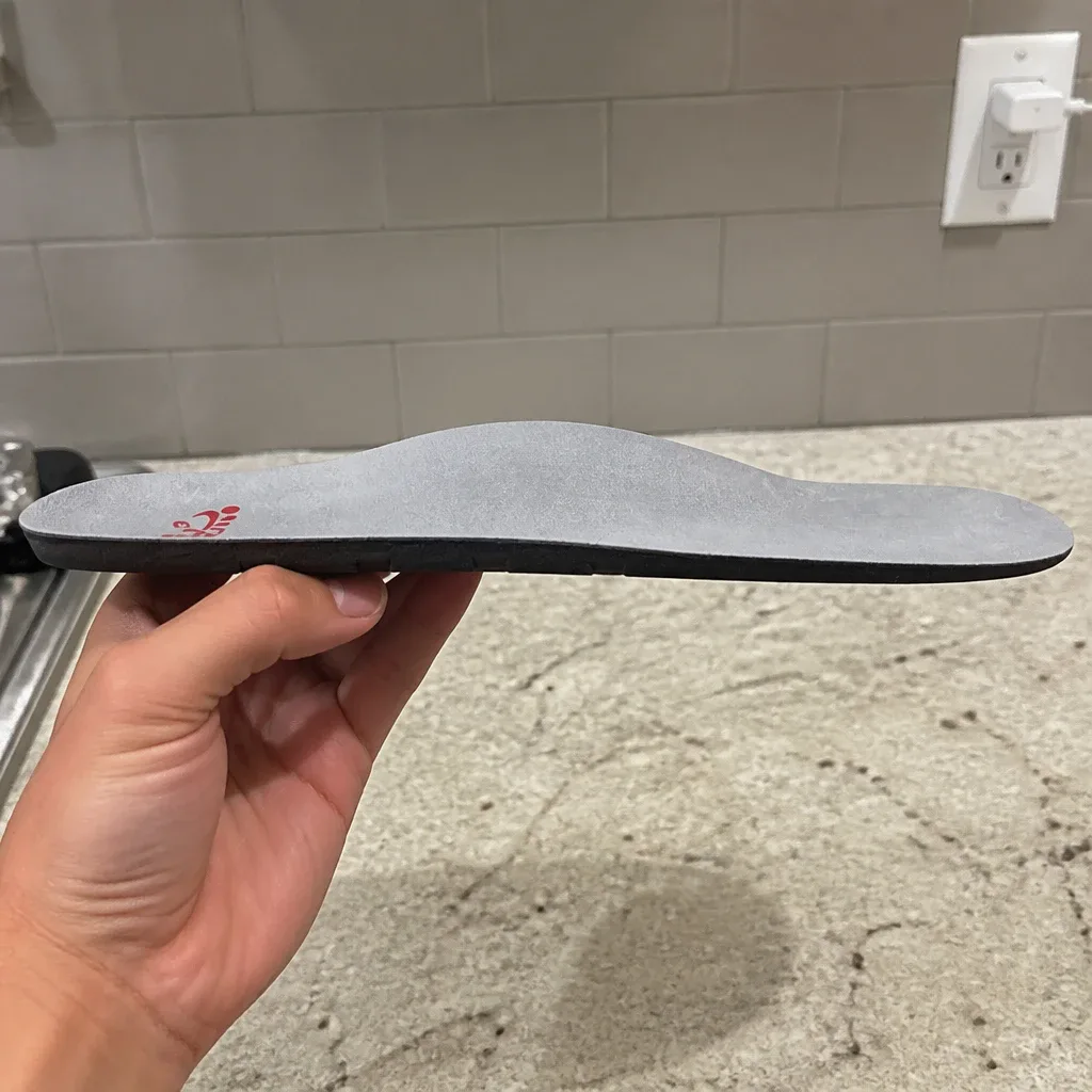 An Archies Full-Length Casual arch support insole held sideways, showing the arch height profile