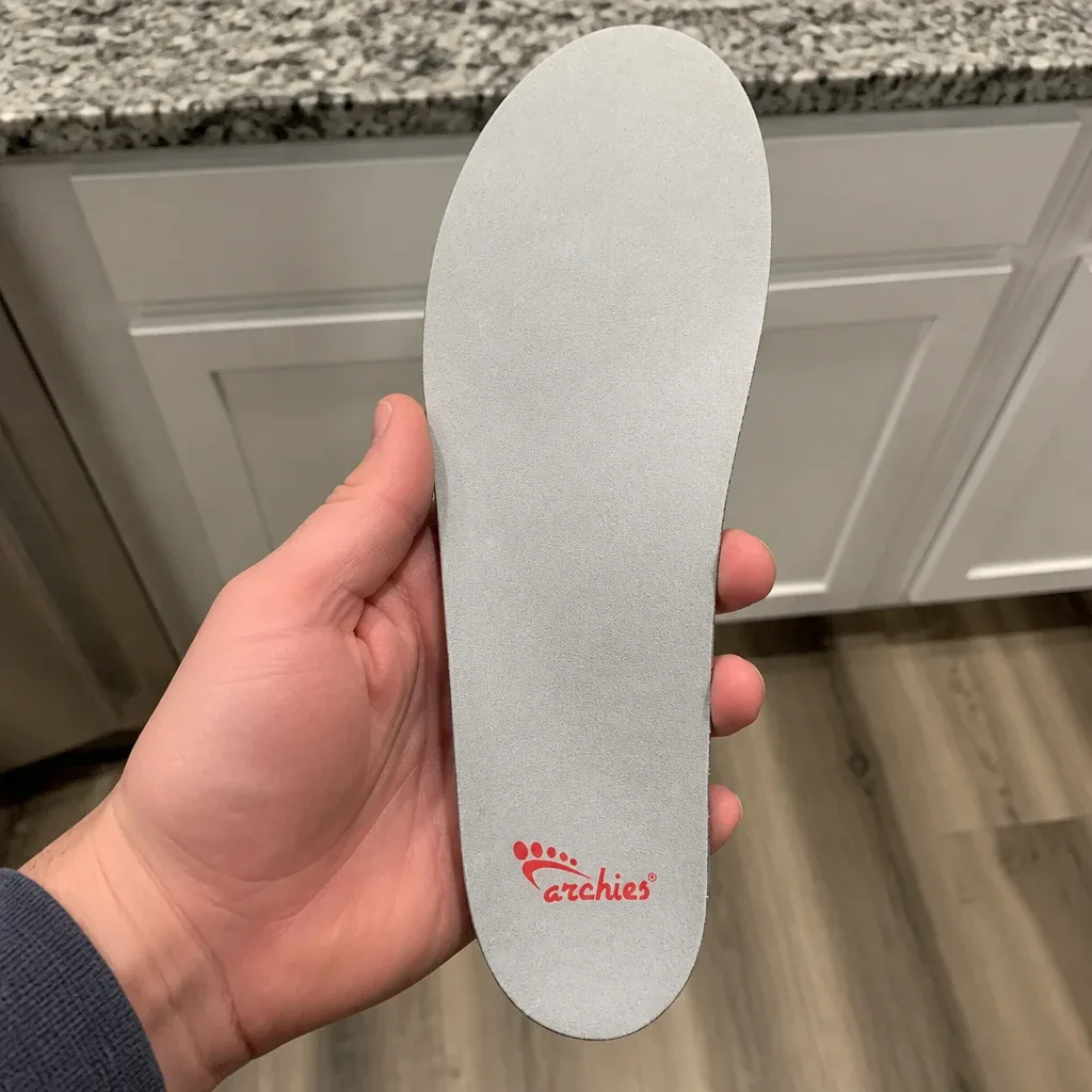 An Archies Full-Length Casual arch support insole held in hand, showing the molded heel cup