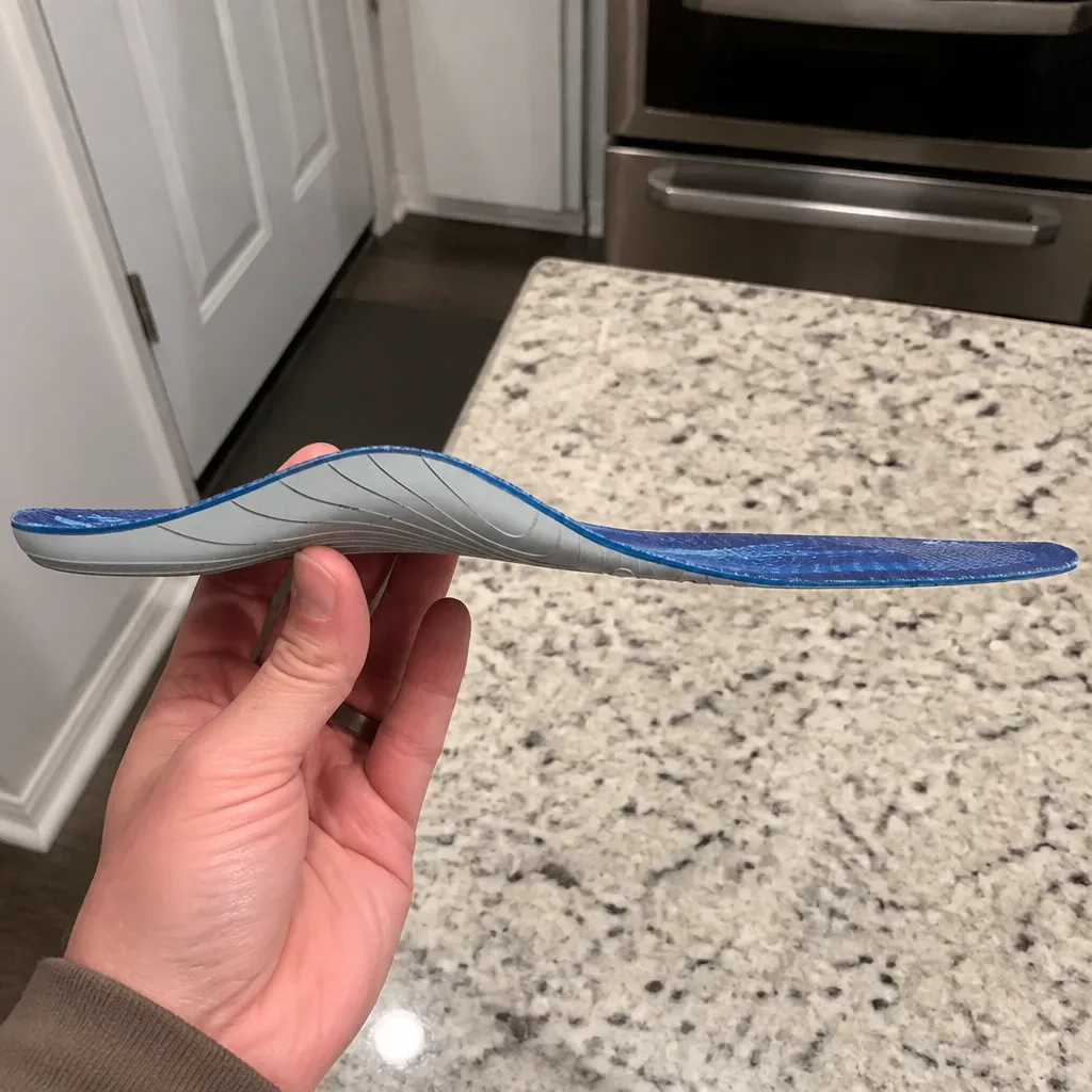 A Bauer Aetrex Fit A skate orthotic held sideways, showing the dual-density profile