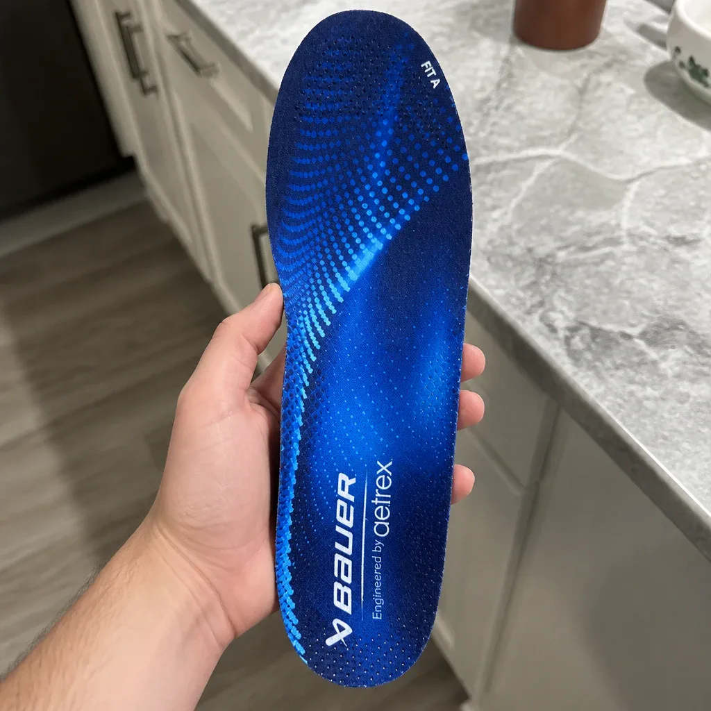 A Bauer Aetrex Fit A skate orthotic held in hand, showing the arch post and heel cup
