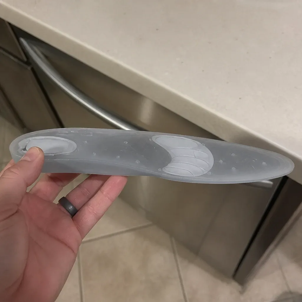 A Bauerfeind ViscoPed S silicone insole held sideways, showing the molded profile