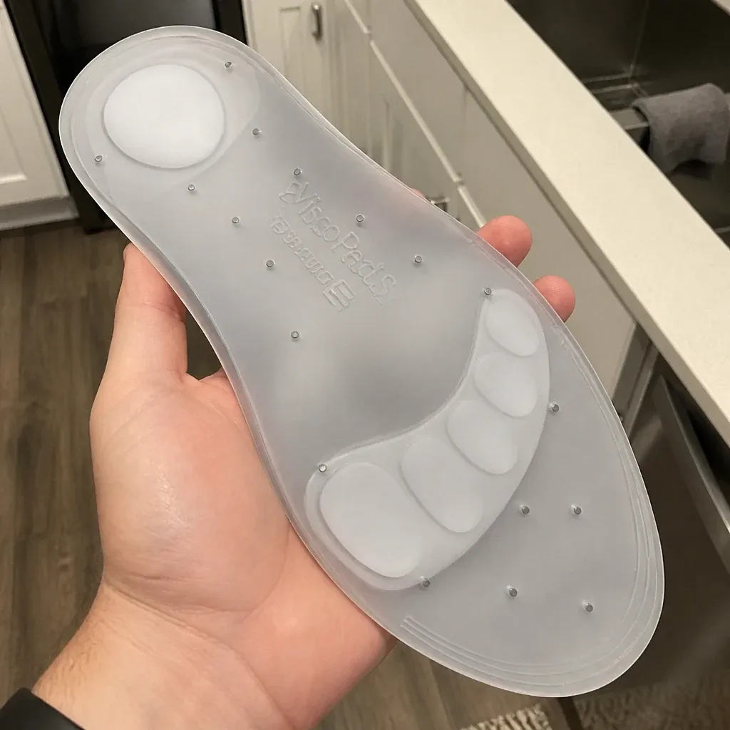 A Bauerfeind ViscoPed S silicone insole held in hand, showing the metatarsal padding and ventilation openings