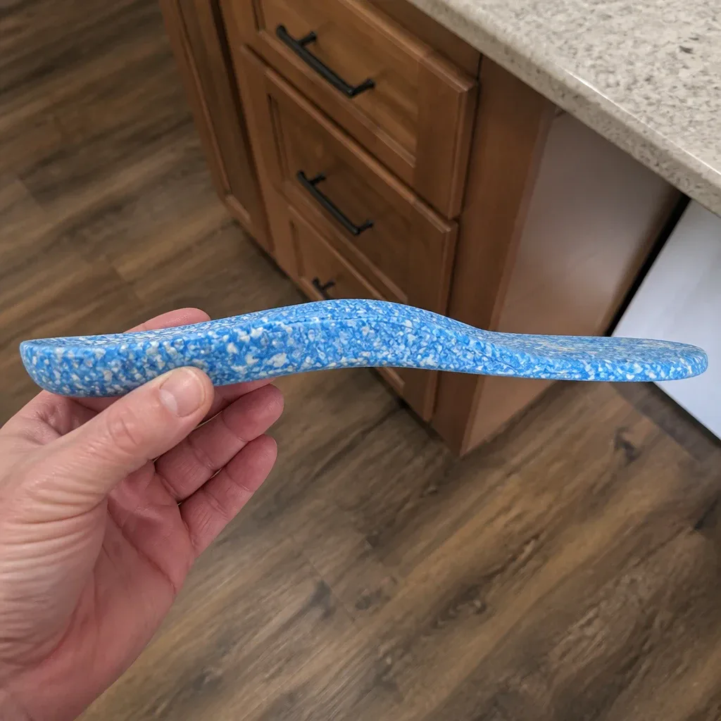 A Blumaka NonSlip Performance Insole shown from the side, held in hand to display its profile