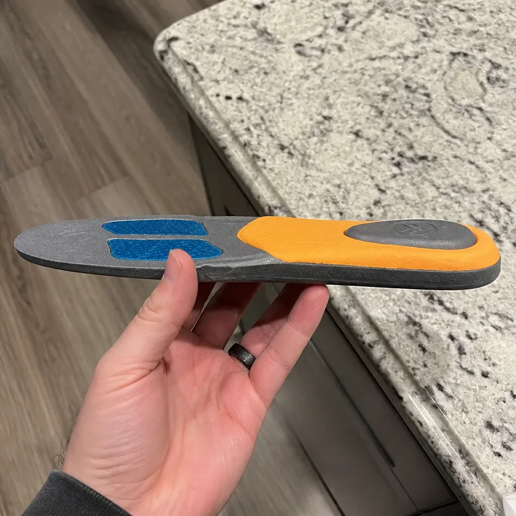 A Hawx Ground Support Work Boot Insole held sideways to show its arch profile and heel cup depth