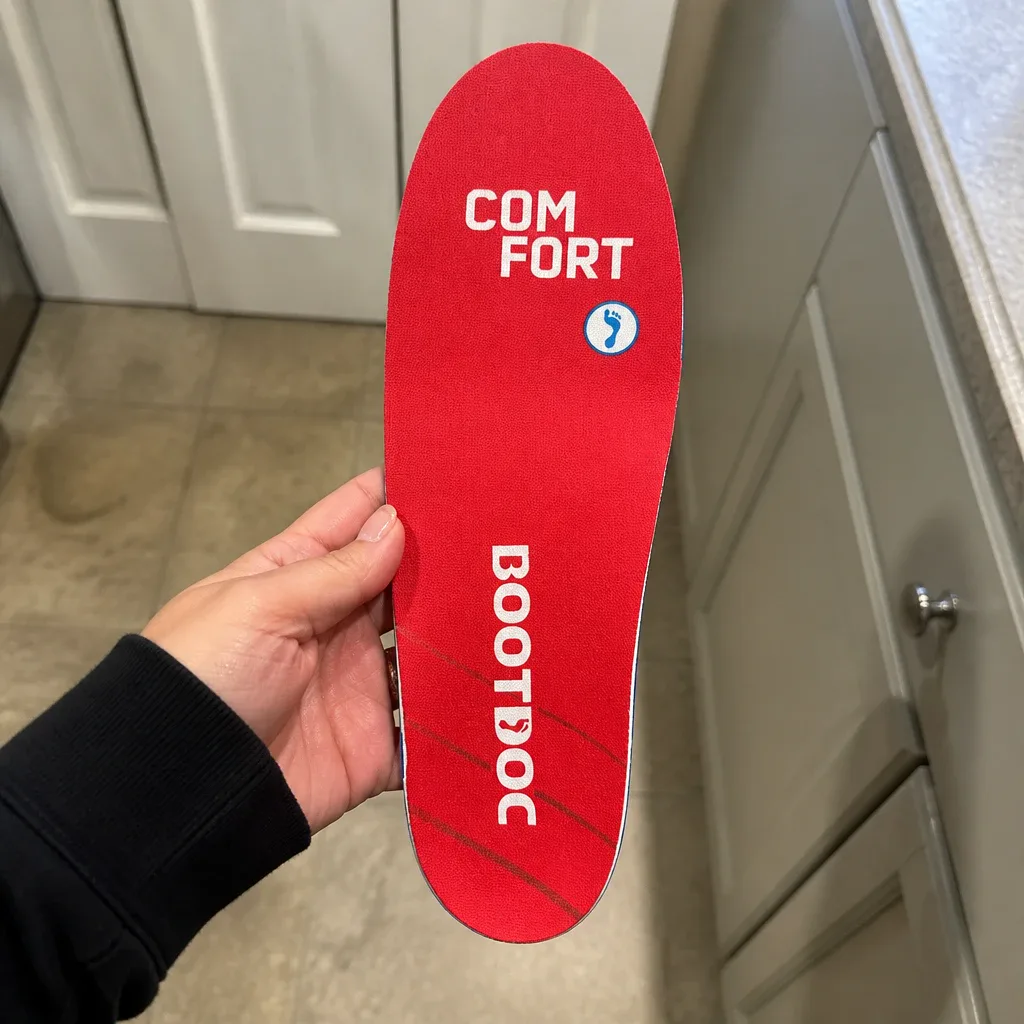 Holding a Boot Doc Comfort Insole to check the shell and top cover