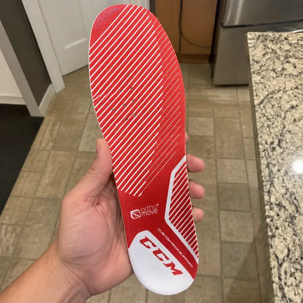 Holding a CCM Orthomove hockey skate insole to show the molded arch shell
