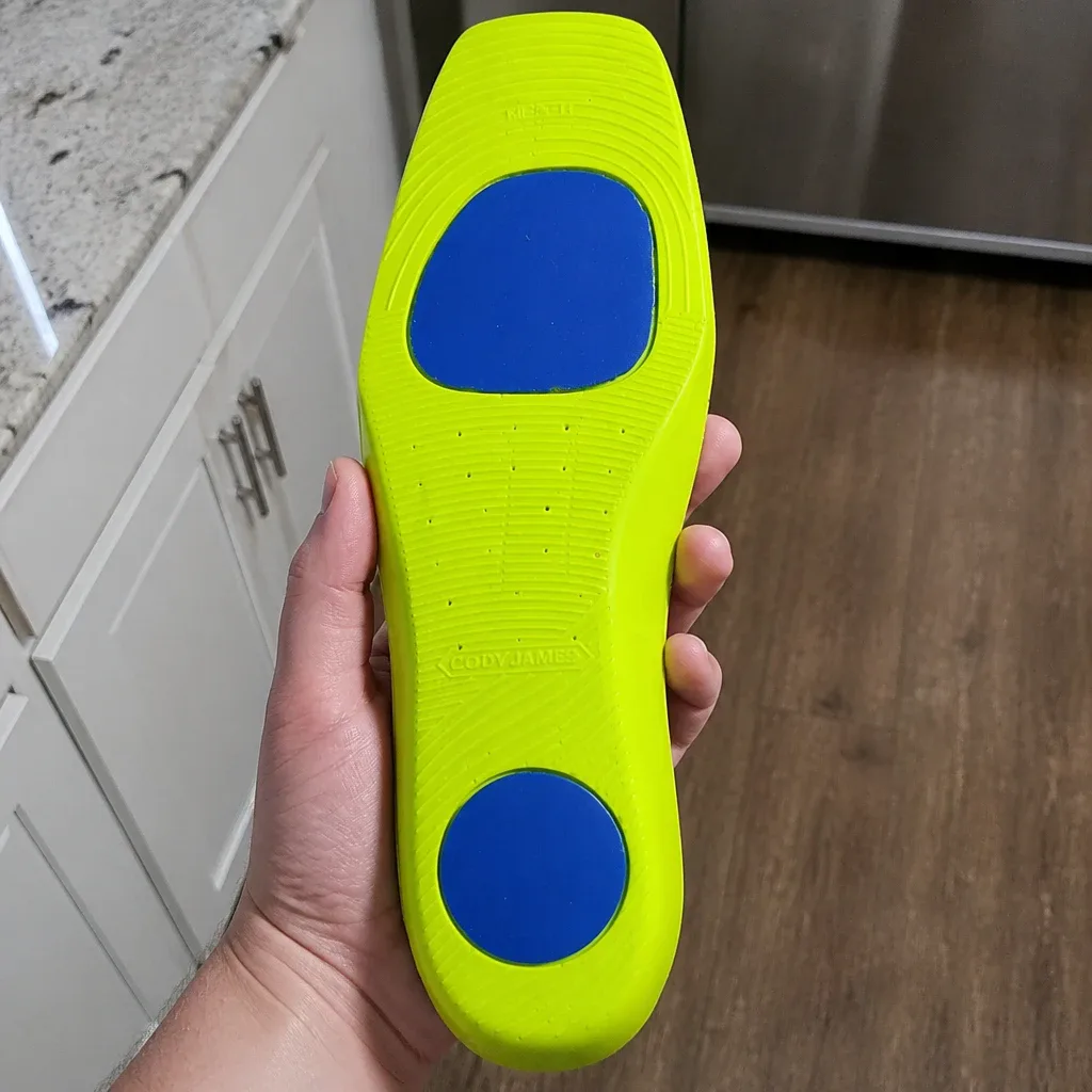 Holding a Cody James Xero Gravity Comfort Insole to show the three-layer construction