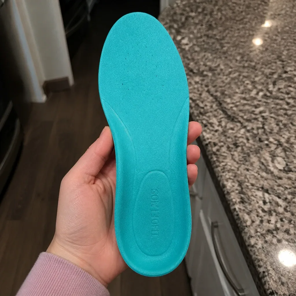 A Comfort Fit Orthotics insole held in hand, showing the semi-rigid shell and top cover