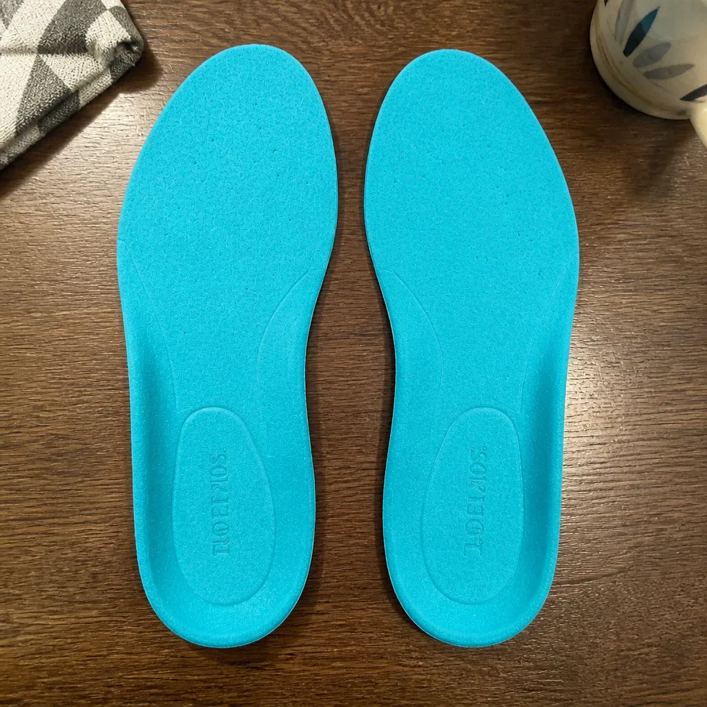 Comfort Fit Orthotics insoles resting on a kitchen table next to the shoes they were fitted into