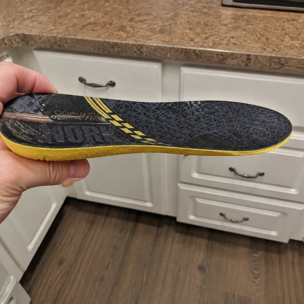 A Copper Fit Work Gear Comfort Insole held sideways, showing the foam profile