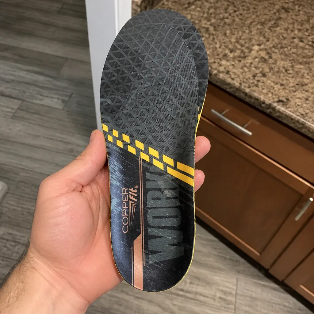 A Copper Fit Work Gear Comfort Insole held in hand, showing the copper-infused top layer