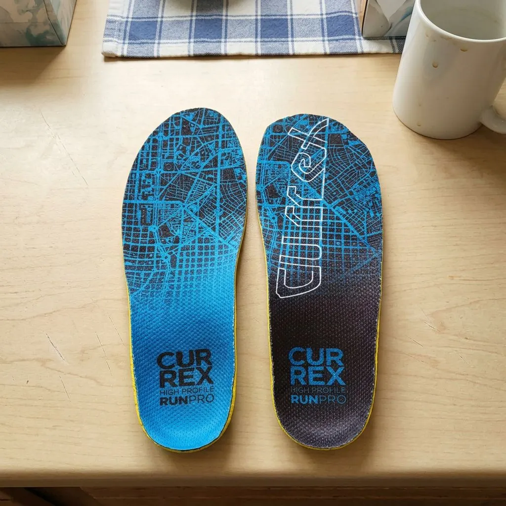 A single CURREX RunPro High Profile insole held up close, showing the map-print top cover and printed branding