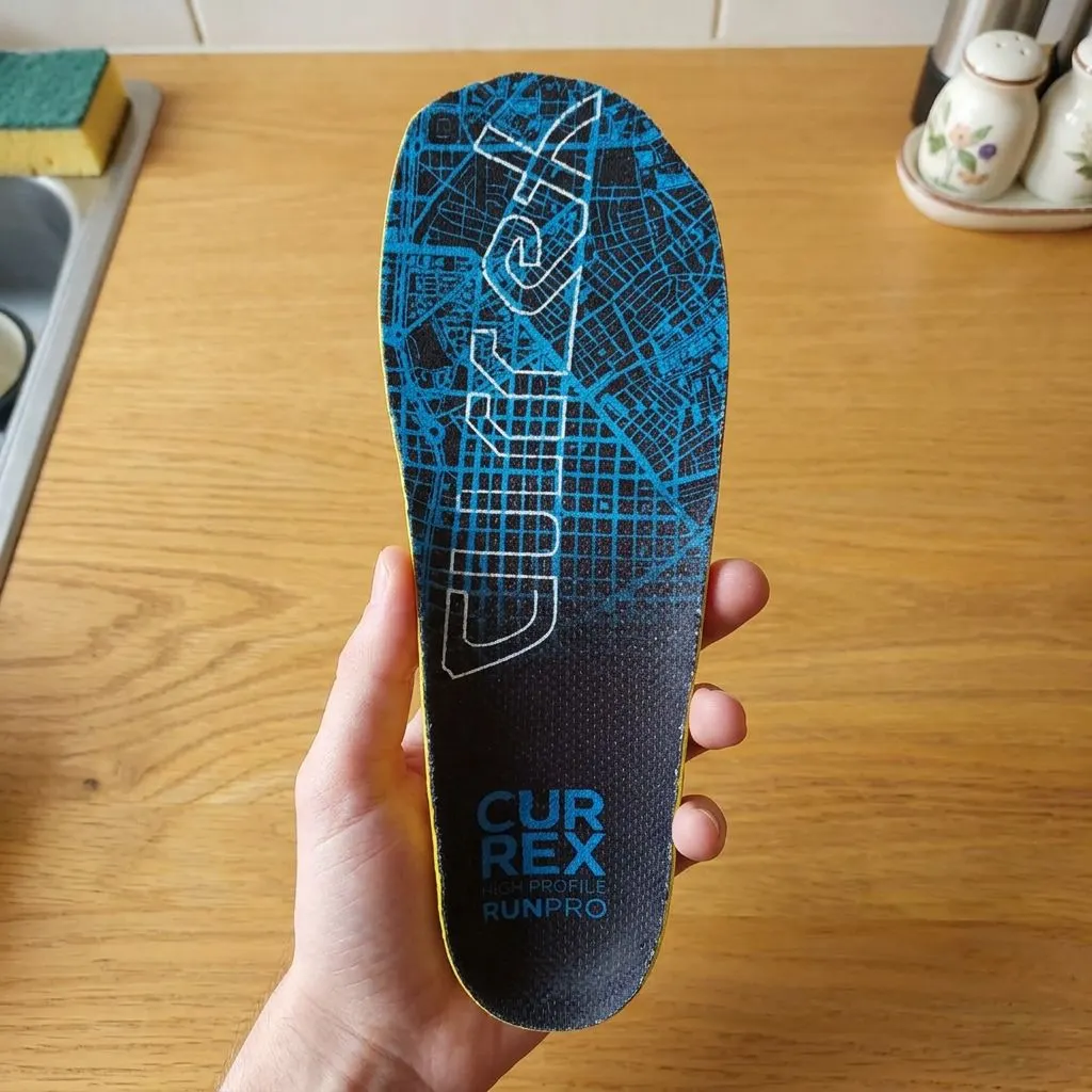 A pair of CURREX RunPro insoles laid side by side on a table, showing the map-print top cover