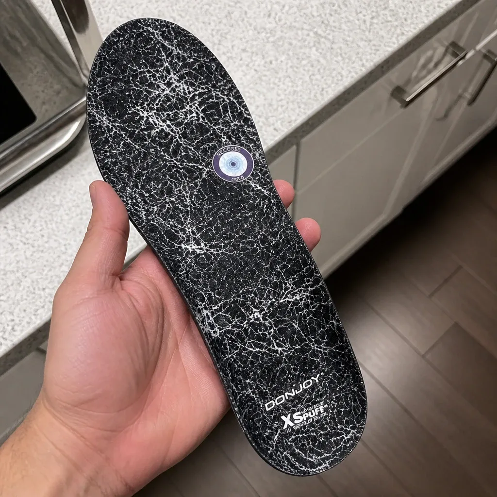 Holding the DonJoy insole in hand to show the recessed metatarsal pocket and heel cup