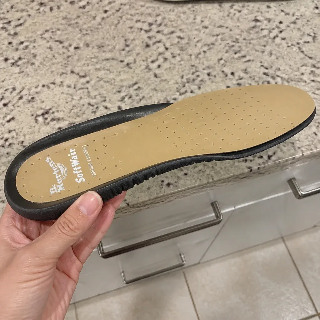 Dr. Martens Softwair insole held sideways in hand to show heel and arch profile