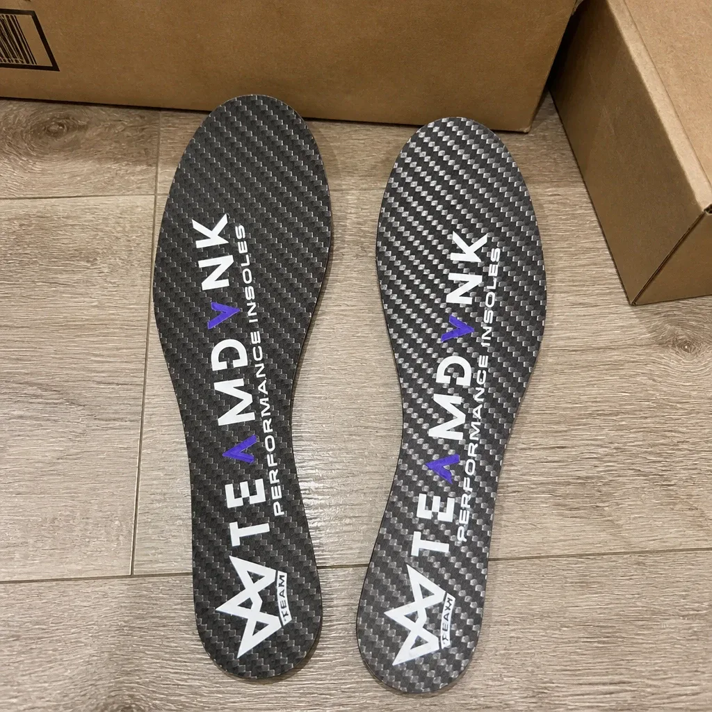 DVNK carbon fiber insoles laid out next to their retail box on the floor