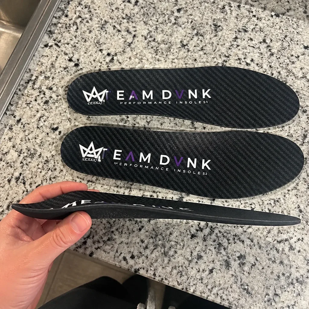 A DVNK carbon fiber insole viewed from the side, showing the arch profile