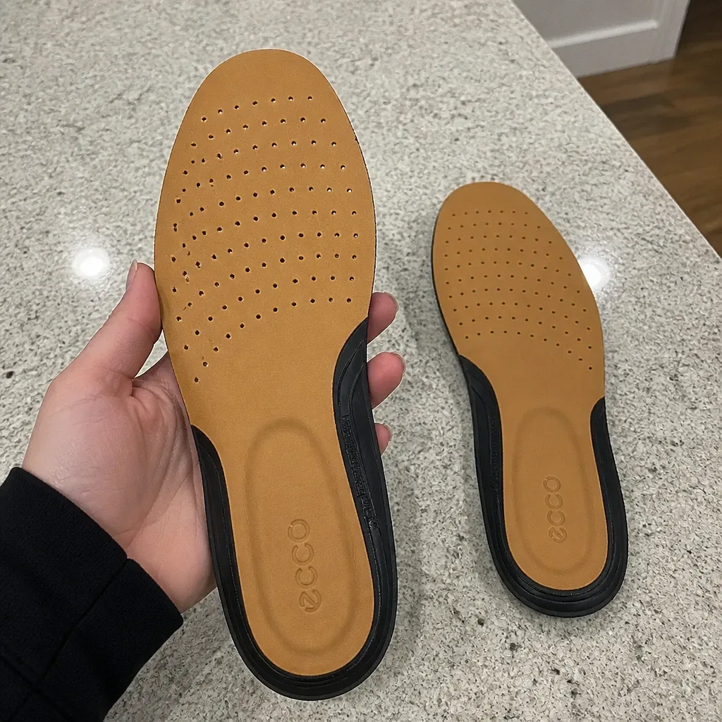 An ECCO Comfort Supreme Leather insole held in hand, showing the perforated leather top cover