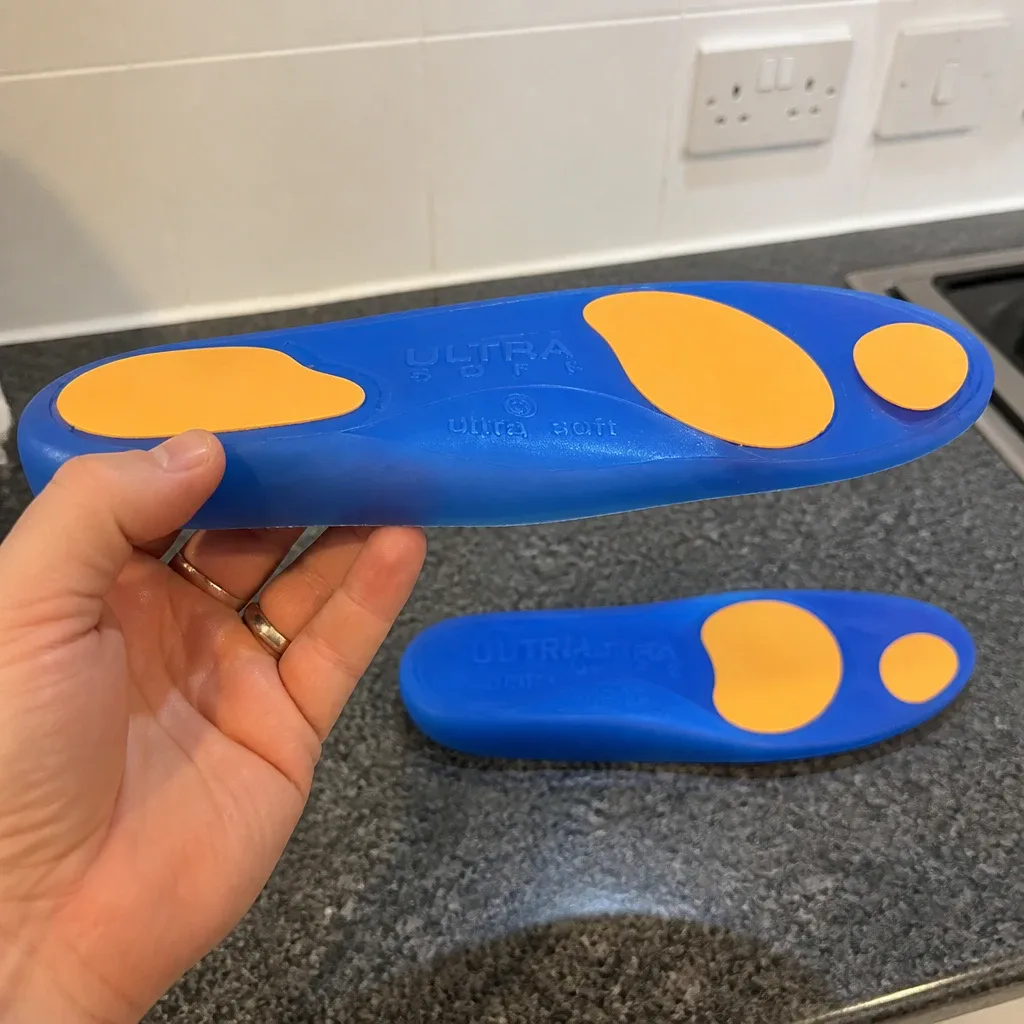 An Ergonx Ultra Soft insole held sideways showing the heel cup and arch profile