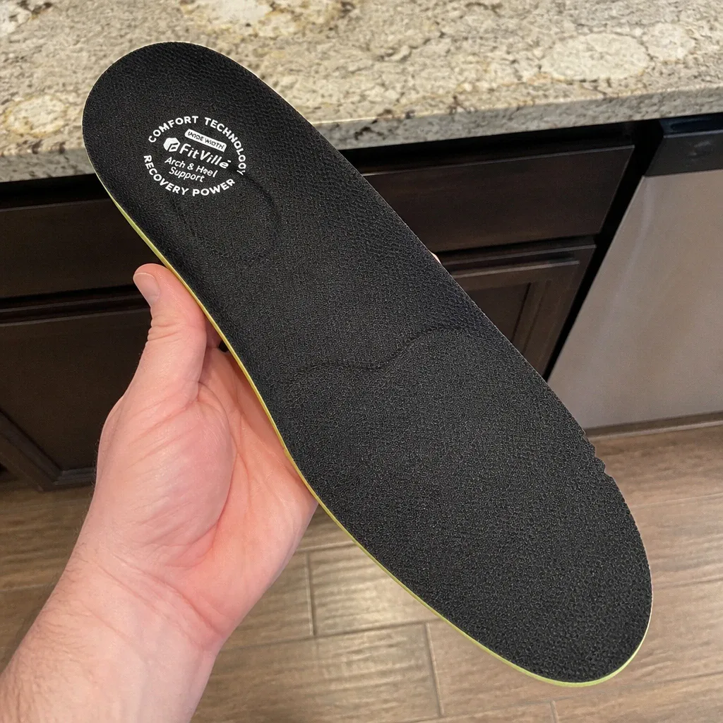 A Fitville Comfort insole held in hand, showing the heel cup and sponge foam top layer