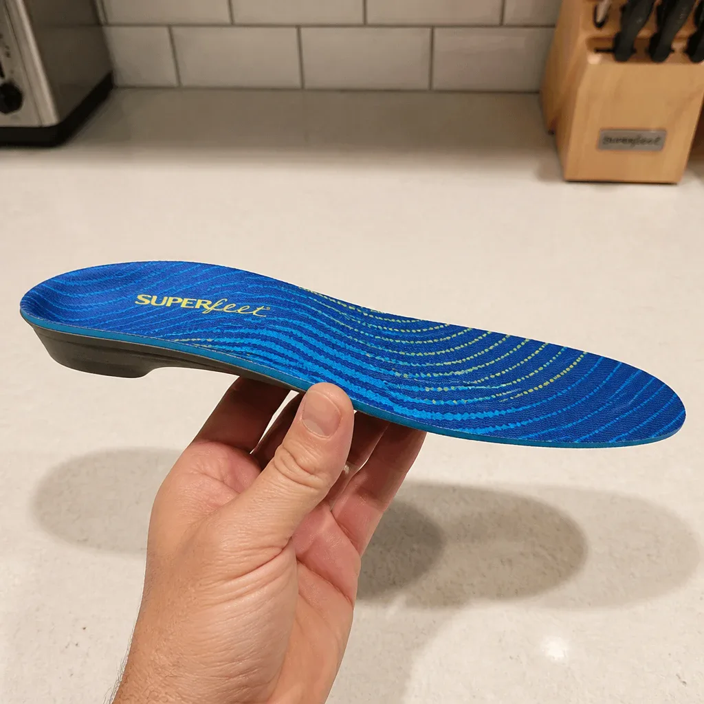 A Fleet Feet Superfeet Run Support High Arch insole held sideways showing the arch profile