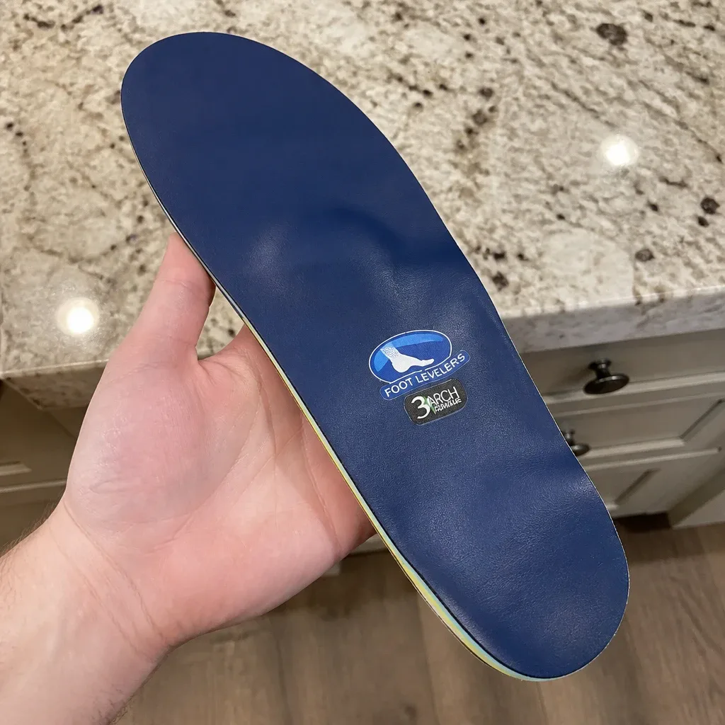 Holding the Foot Levelers Elite Comfort orthotic to show the heel cup and arch shell