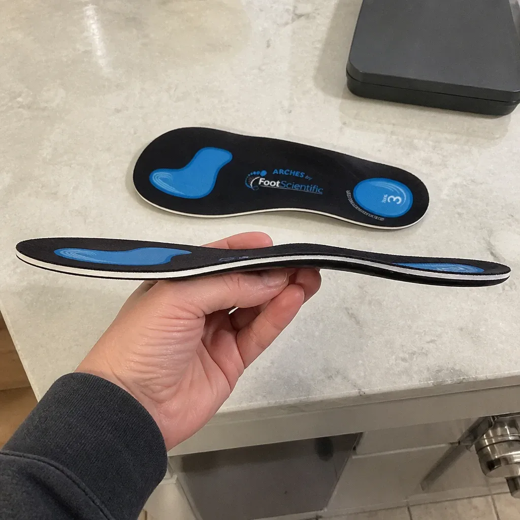 A FootScientific Arches Type 3 orthotic held sideways, showing the arch profile