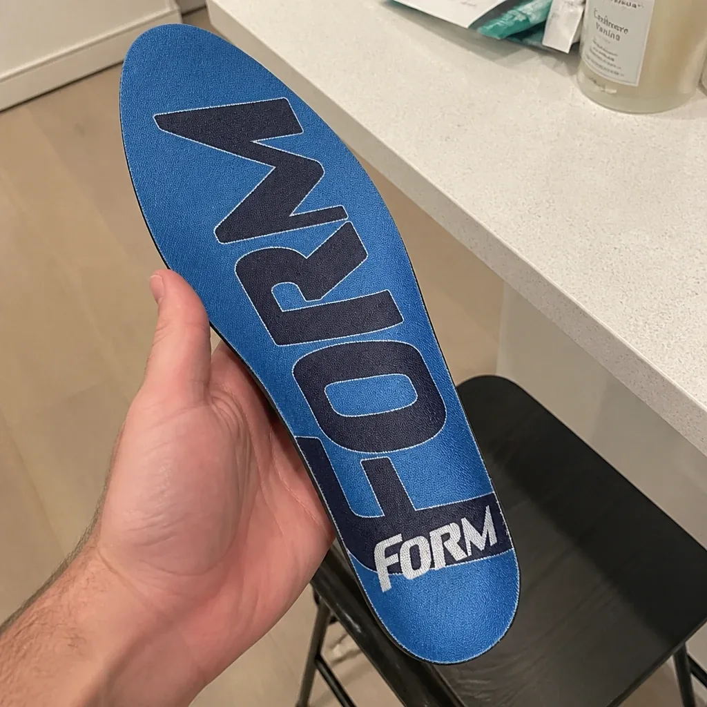 A FORM Maximum Support insole held in hand showing the arch shelf and heel cup