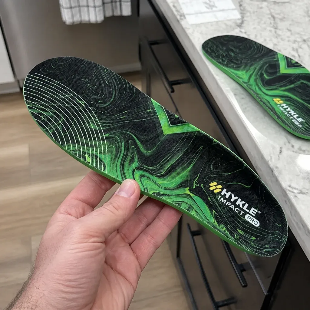 A HYKLE Impact Pro insole held in hand showing the raised arch and heel cup