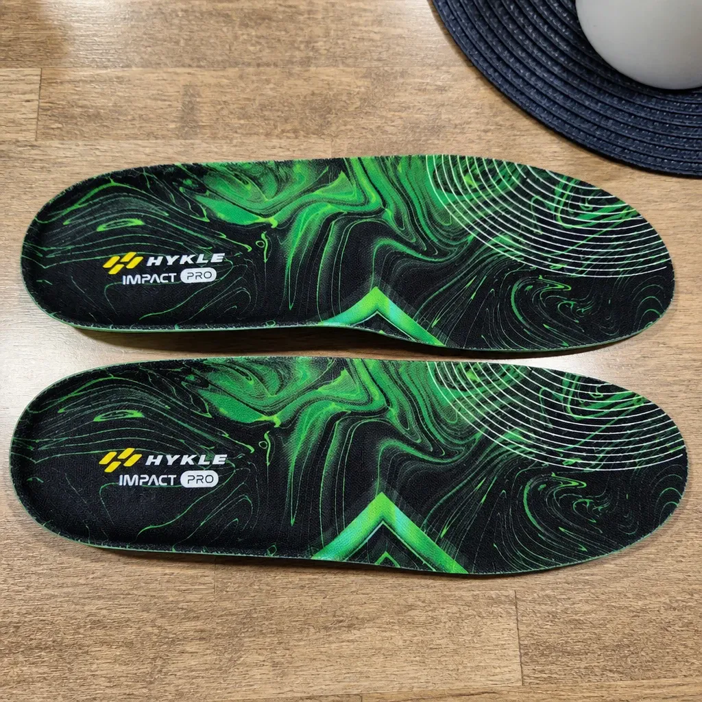 A pair of HYKLE Impact Pro insoles top side up on a wooden kitchen table