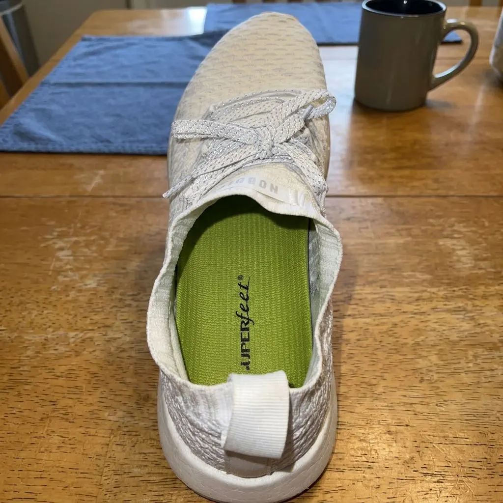 A Superfeet Green insole seated inside a white athletic shoe